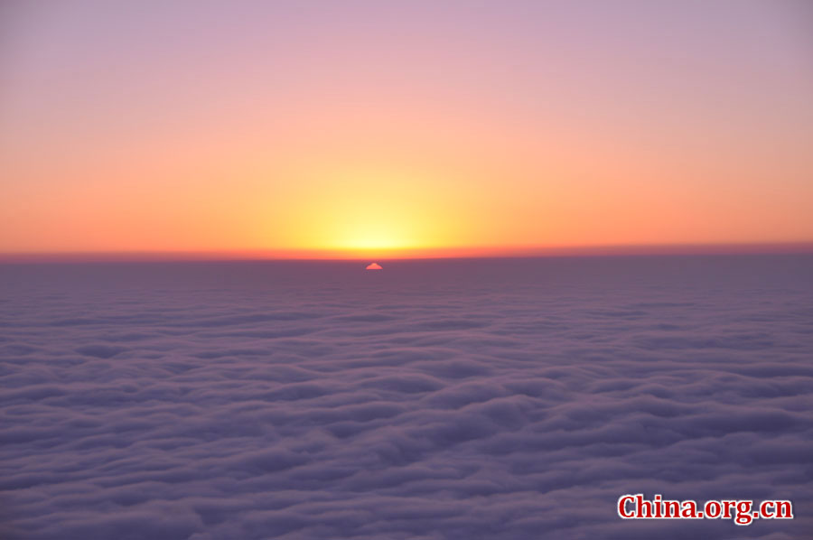 日出是峨眉山顶的又一自然殊景，奇妙壮观。在海拔3000多米的峨眉山金顶，远望东方，地平线在水平视线以下，橙红的太阳冒出水平线，伴有云层作陪，尽显浩瀚壮阔。[中国网 陈祥昭 摄]