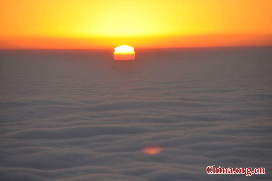 日出是峨眉山顶的又一自然殊景，奇妙壮观。在海拔3000多米的峨眉山金顶，远望东方，地平线在水平视线以下，橙红的太阳冒出水平线，伴有云层作陪，尽显浩瀚壮阔。[中国网 陈祥昭 摄]