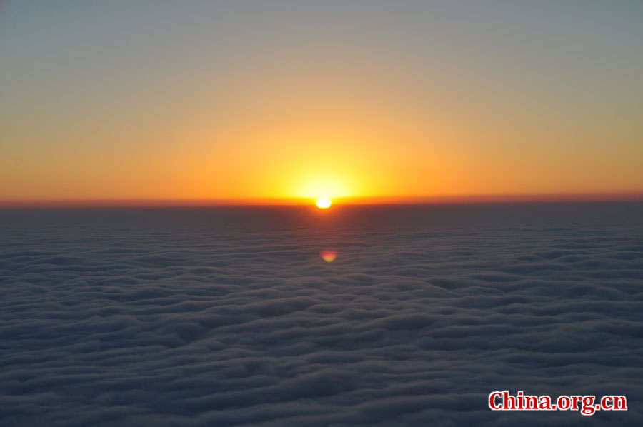 日出是峨眉山顶的又一自然殊景，奇妙壮观。在海拔3000多米的峨眉山金顶，远望东方，地平线在水平视线以下，橙红的太阳冒出水平线，伴有云层作陪，尽显浩瀚壮阔。[中国网 陈祥昭 摄]