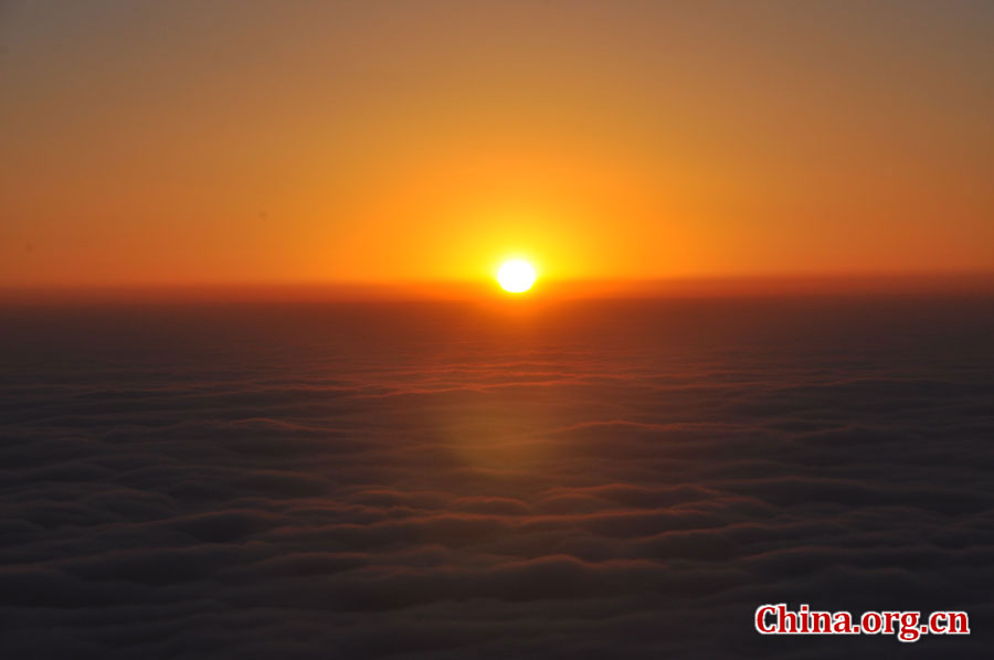 日出是峨眉山顶的又一自然殊景，奇妙壮观。在海拔3000多米的峨眉山金顶，远望东方，地平线在水平视线以下，橙红的太阳冒出水平线，伴有云层作陪，尽显浩瀚壮阔。[中国网 陈祥昭 摄]