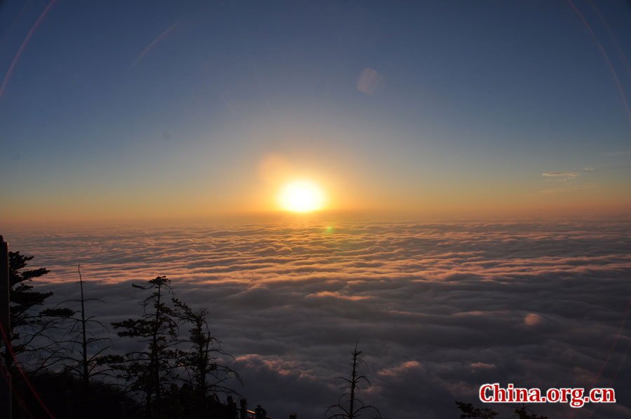 日出是峨眉山顶的又一自然殊景，奇妙壮观。在海拔3000多米的峨眉山金顶，远望东方，地平线在水平视线以下，橙红的太阳冒出水平线，伴有云层作陪，尽显浩瀚壮阔。[中国网 陈祥昭 摄]