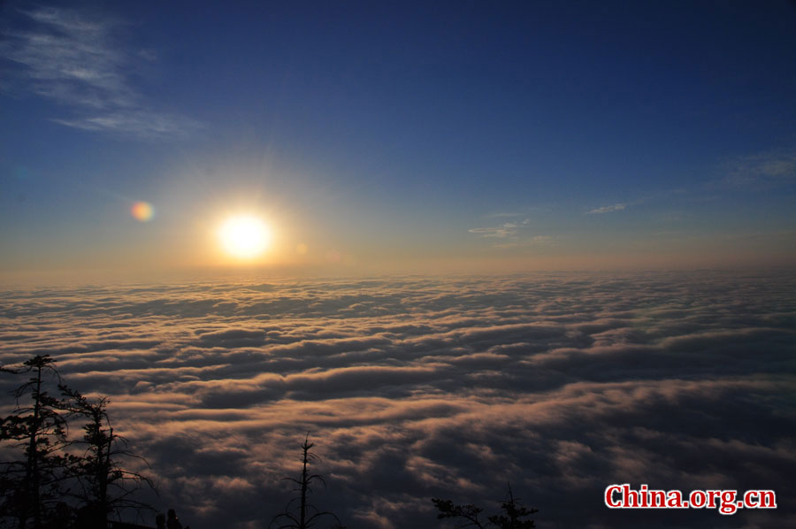 日出是峨眉山顶的又一自然殊景，奇妙壮观。在海拔3000多米的峨眉山金顶，远望东方，地平线在水平视线以下，橙红的太阳冒出水平线，伴有云层作陪，尽显浩瀚壮阔。[中国网 陈祥昭 摄]