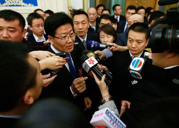 Zhang Chunxian, Party chief of the Xinjiang Uygur autonomous region, is surrounded by reporters after a panel discussion of the Government Work Report in Beijing, March 6, 2014. [Photo/China Daily]