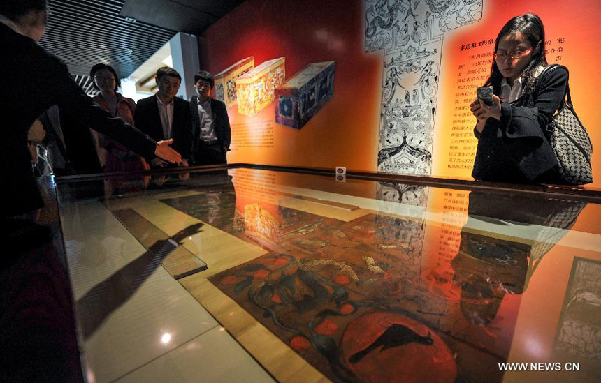 Visitors watch the the T-shaped painting on silk, the highlight of the Hunan Provincial Museum, at the museum in Changsha, capital of central China&apos;s Hunan Province, March 28, 2014. More than 50 pieces (sets) of cultural relics from the Mawangdui Tombs of the Han Dynasty (206 B.C. - 220 A.D.), located in the eastern suburbs of Changsha, will be officially re-presented at the museum from March 29. 