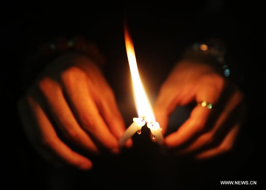 A man holds candles to pray for the passengers aboard the missing Malaysia Airlines MH370 in Kuala Lumpur, March 30, 2014. [Xinhua/Wang Shen]