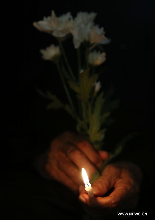 A man holds candles and flowers to pray for the passengers aboard the missing Malaysia Airlines MH370 in Kuala Lumpur, March 30, 2014. [Xinhua/Wang Shen]
