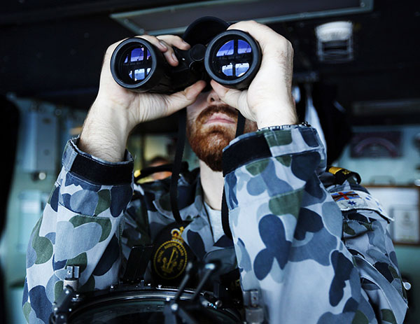 Maritime Warfare Officer, Sub Lieutenant Officer Samuel Archibald, looks through binoculars on the bridge of the Australian Navy ship HMAS Perth in the southern Indian Ocean, during the search for the missing Malaysian Airlines flight MH370, in this picture released by the Australian Defence Force on April 8, 2014. [Photo/China Daily via Agencies]