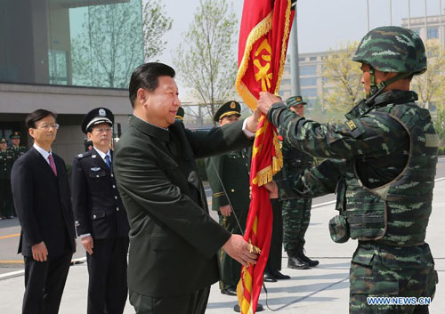 Chinese President Xi Jinping (L, front), who is also chairman of the Central Military Commission (CMC), presents a new flag to the 'Falcon Commando Unit', an elite police counter-terror brigade, at the Special Police Academy of the Chinese People's Armed Police Force, in Beijing, capital of China, April 9, 2014. [Li Gang/Xinhua]