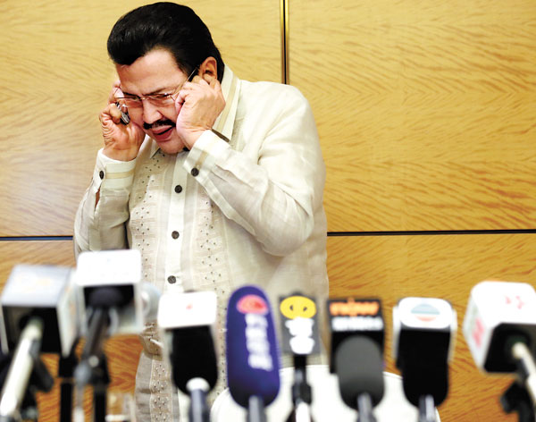 Joseph Estrada, mayor of Manila, tends to earpiece problems at a news conference in Hong Kong on Wednesday. Hong Kong and the Philippines have reached a consensus over a diplomatic row arising from a 2010 hijack incident. [Photo/China Daily] 
