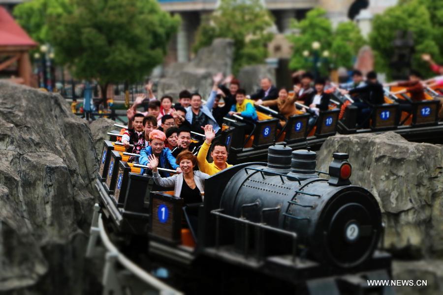 Tourists take a roller coaster at the Fantawild Adventure amusement park in Wuhu, east China&apos;s Anhui Province, April 28, 2014. Many people in Wuhu went to amusement parks to enjoy spring outdoors.