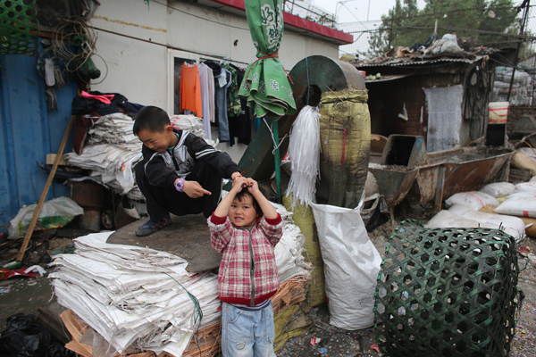Children play amid recycled materials near their house. [Photo/China Daily]