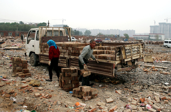 Workers collect bricks in the demolished section of Dongxiaokou village. 