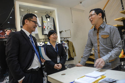 Client managers from Bank of Taizhou visit a clothing vendor to ask about his loan needs in Taizhou, Zhejiang province. New yuan loans amounted to 774.7 billion yuan ($124.95 billion) in April, down from March's 1.05 trillion yuan. [Xinhua]