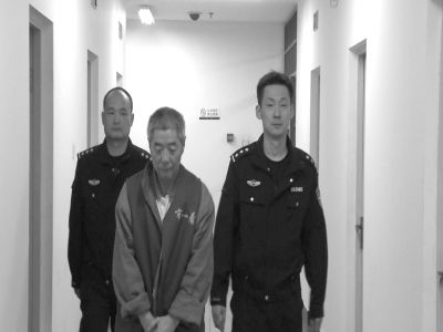 The undated photo shows Xiang Nanfu escorted by police officers. [Photo/Beijing Times] 
