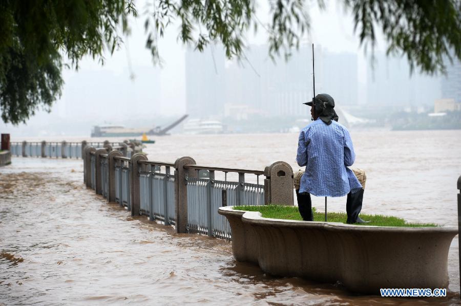 A man goes fishing at a submerged sidewalk along Xiangjiang River in Changsha, capital of central China's Hunan Province, May 26, 2014. Hunan issued the red alert of floods on May 25 as continuous downpours hit many parts of the province. A total of 400,000 people were affected and 16,776 displaced with the collapse of 520 houses. [Photo/Xinhua]