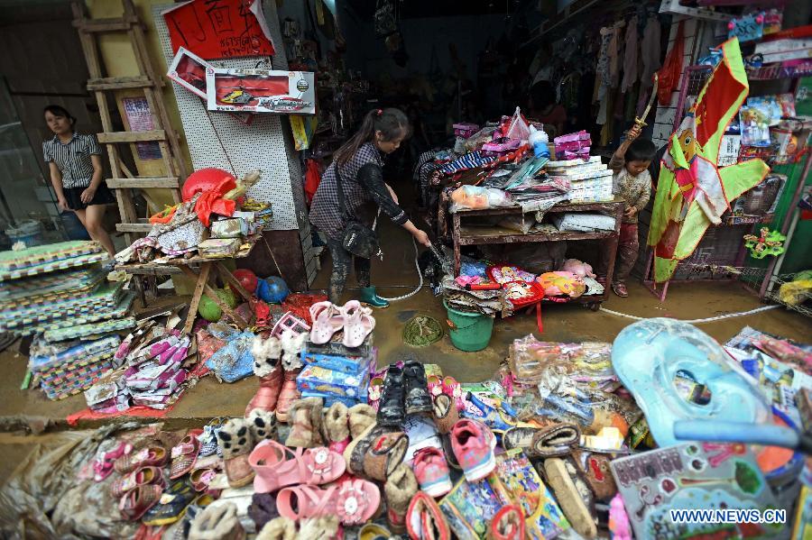 A shopkeeper cleans goods soaked by flood water in front of a grocery in Chenjiafang Town, Shaoyang County, central China's Hunan Province, May 26, 2014. Hunan issued the red alert of floods on May 25 as continuous downpours hit many parts of the province. A total of 400,000 people were affected and 16,776 displaced with the collapse of 520 houses. [Photo/Xinhua]