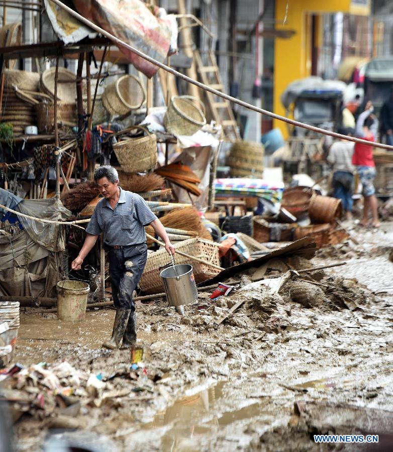 A man walks on a muddy road after a flood withdrew in Chenjiafang Town, Shaoyang County, central China's Hunan Province, May 26, 2014. Hunan issued the red alert of floods on May 25 as continuous downpours hit many parts of the province. A total of 400,000 people were affected and 16,776 displaced with the collapse of 520 houses. [Photo/Xinhua]