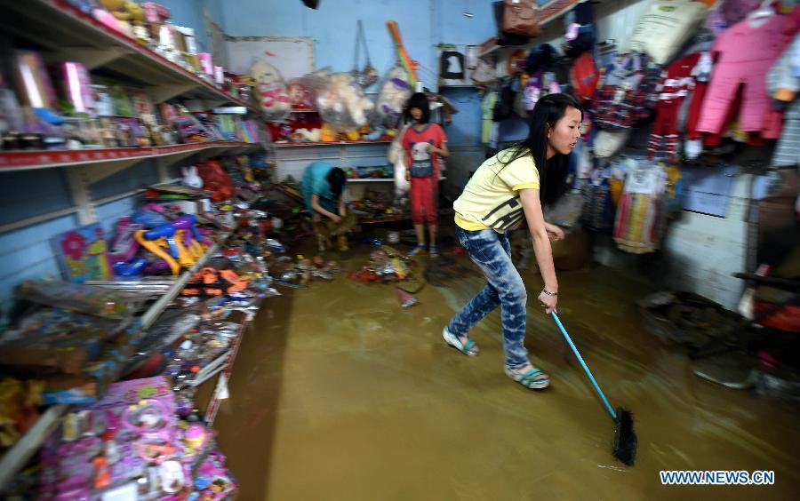 A girl sweeps murky water from a flooded grocery in Chenjiafang Town, Shaoyang County, central China's Hunan Province, May 26, 2014. Hunan issued the red alert of floods on May 25 as continuous downpours hit many parts of the province. A total of 400,000 people were affected and 16,776 displaced with the collapse of 520 houses. [Photo/Xinhua]