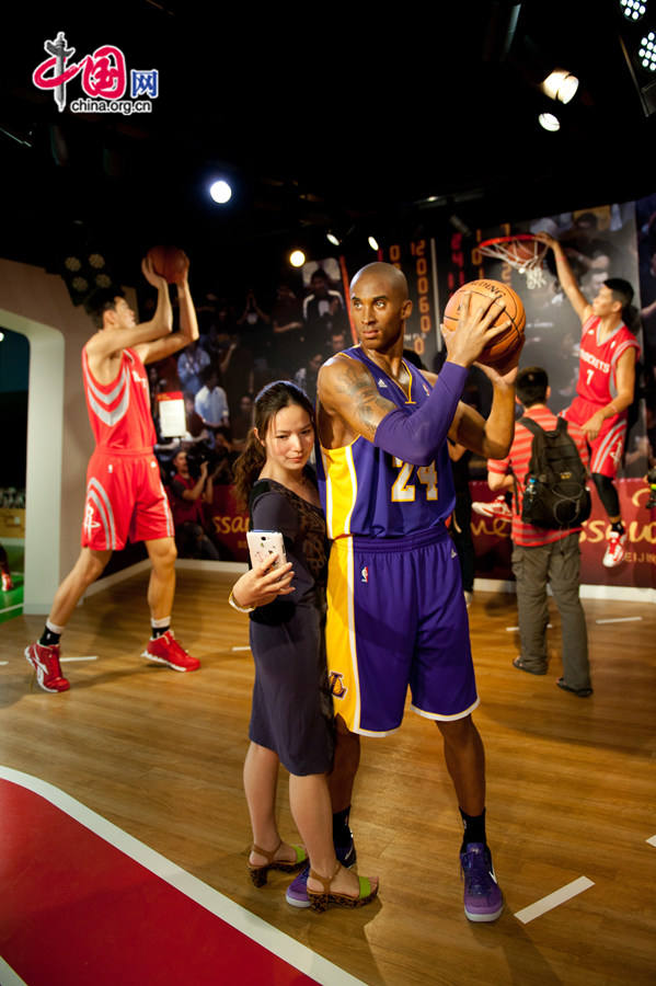 A visitor trys to take a selfie with the wax figure of Kobe Bryant at Madame Tussauds Beijing on Thursday. The wax museum will be officially open to public on May 31, 2014. [Photo by Chen Boyuan / China.org.cn]
