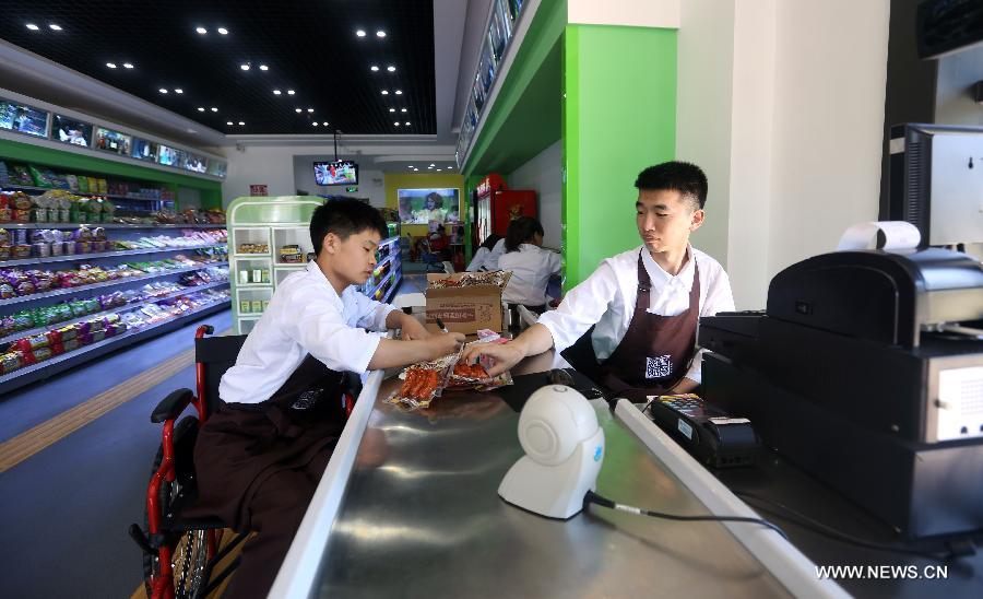 Staffers work at an accessible supermarket during its soft operation in Shenyang, capital of northeast China&apos;s Liaoning province, May 30, 2014. The market with barrier-free designs including Braille tags, blind tracks and free loans of wheelchairs, will officially open in June. All employees of the market are disabled people.