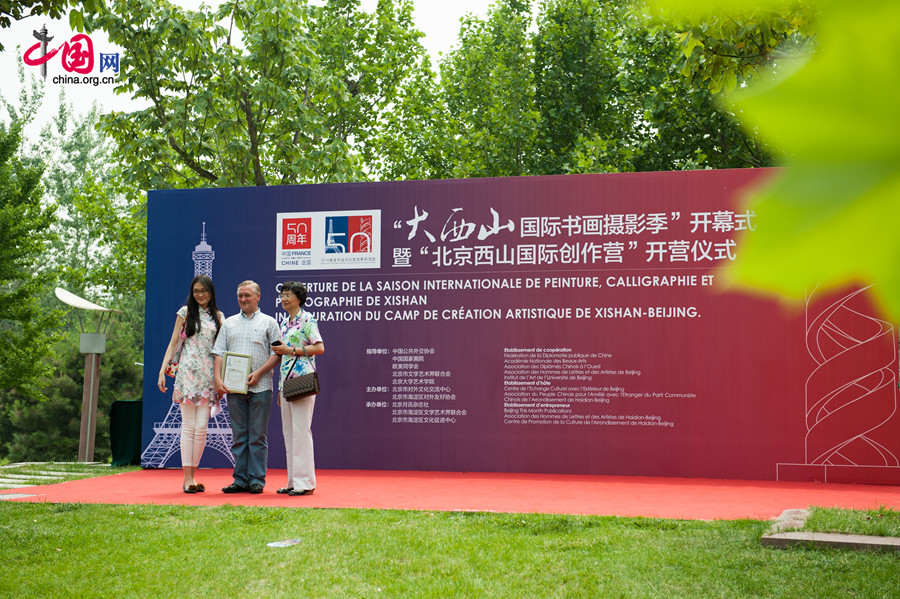 French photographer Philippe Bourgois (C) and his friend pose for photo before a background at the Opening Ceremony of Xishan International Season of Painting, Caligraphy and Photography held on Saturday, May 31 in the Chinese capital Beijing. [Photo by Chen Boyuan / China.org.cn]