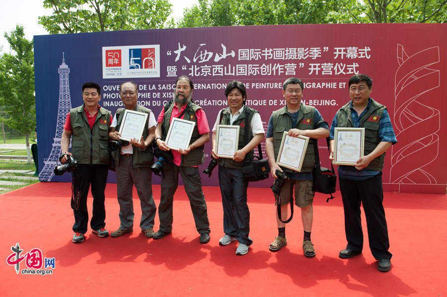 Photographers invited to take part in the artistic season and artistic creation camp pose for photos with certificates of their participation. [Photo by Chen Boyuan / China.org.cn]