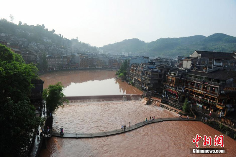 A scenic spot nearly submerged by river water in the Fenghuang Ancient Town, a famous tourist site in central China's Hunan province, attracts many visitors and photographers to the area on June 2, 2014. Recently, continuous rain has created a surge in river-water levels. [Photo: Chinanews.cn/Yang Huafeng]