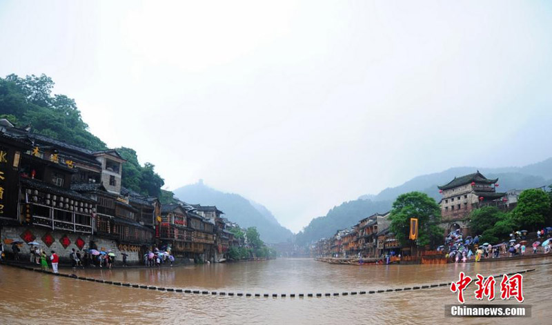 A scenic spot nearly submerged by river water in the Fenghuang Ancient Town, a famous tourist site in central China's Hunan province, attracts many visitors and photographers to the area on June 2, 2014. Recently, continuous rain has created a surge in river-water levels. [Photo: Chinanews.cn/Yang Huafeng] 