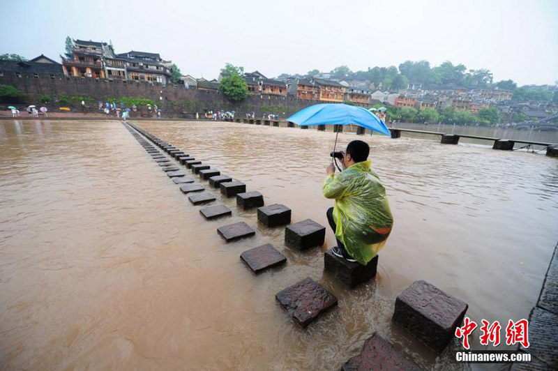 A scenic spot nearly submerged by river water in the Fenghuang Ancient Town, a famous tourist site in central China's Hunan province, attracts many visitors and photographers to the area on June 2, 2014. Recently, continuous rain has created a surge in river-water levels. [Photo: Chinanews.cn/Yang Huafeng] 