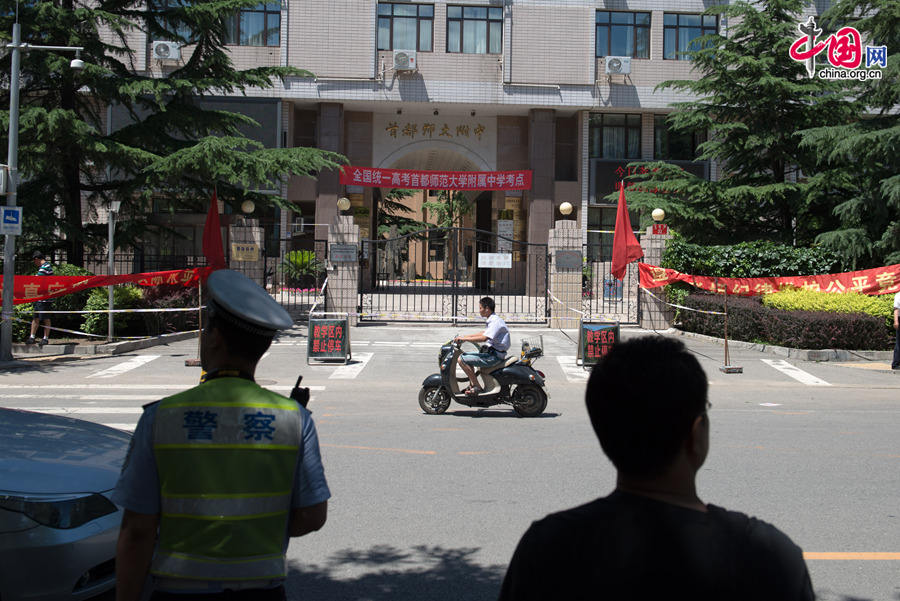 Police officers maintain a partial traffic regulation near the Middle School Affiliated to Capital Normal Univeristy (CNU) on Saturday, June 6, 2014, the first day of the annual national college entrance exam, in a bid to ensure the safety and a noise-free environment for students sitting the exam in the school. Official statistics show a total of 9.39 million students are registered to take the two-day exam, a 3 percent increase than last year. [Photob by Chen Boyuan / China.org.cn]