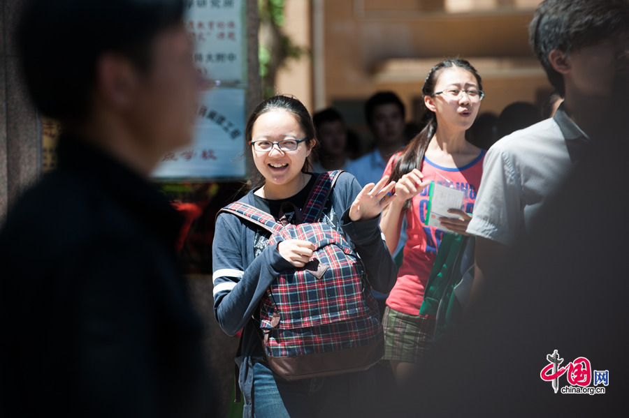 A student beams to her family members waiting outside the school gate at the Middle School Affiliated to Capital Normal Univeristy (CNU) on Saturday, June 6, 2014, after finishing the Exam on Chinese. Official statistics show a total of 9.39 million students are registered to take the two-day exam, a 3 percent increase than last year. [Photob by Chen Boyuan / China.org.cn]