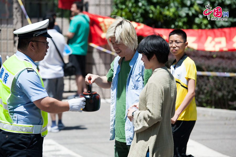 A tea shop offers free drinks to police officers on duty for the annual national college entrance exam at the Middle School Affiliated to Capital Normal University on Saturday, June 6, 2014, partly in a bid to promote itself. [Photo by Chen Boyuan / China.org.cn]