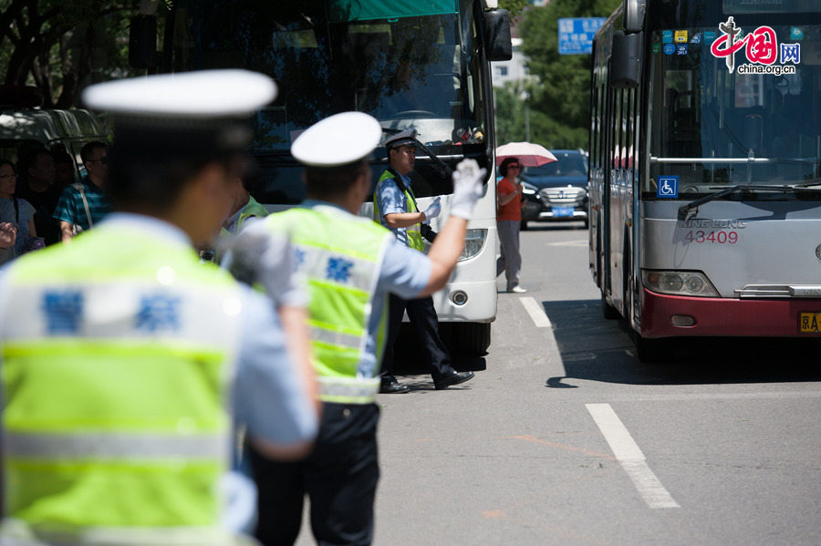 Police officers direct traffic at the street before the Middle School Affiliated to Capital Normal University, a site for the annual national college entrance exam, on Saturday, June 6, 2014, to ensure the safety and a noise-free environment for test takers. [Photo by Chen Boyuan / China.org.cn]