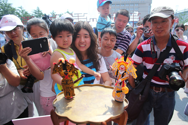 Spectators in Beijing look at a pair of locally handcrafted toys at the ninth annual China Cultural Heritage Day. The celebrations take place all over the country with Jiangdezhen, Jiangxi province, as the main host city. [Photo / China Daily]