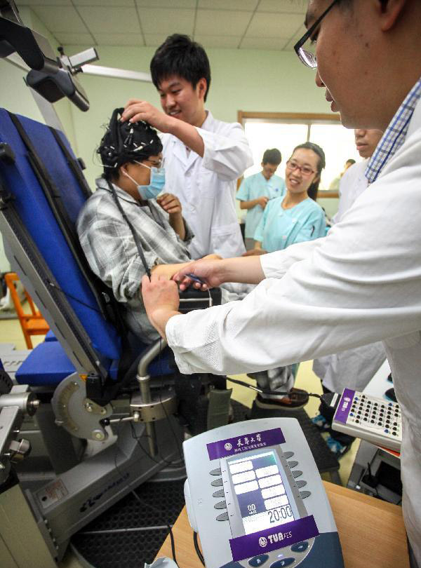 The photo, taken on June 14, 2014, shows a patient, surnamed Dong, uses the robot to help her physical rehabilitation treatment. [Photo: Xinhua]