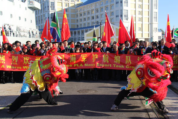 中南两国友人打开横幅、表演舞狮对编队的到访表示欢迎。