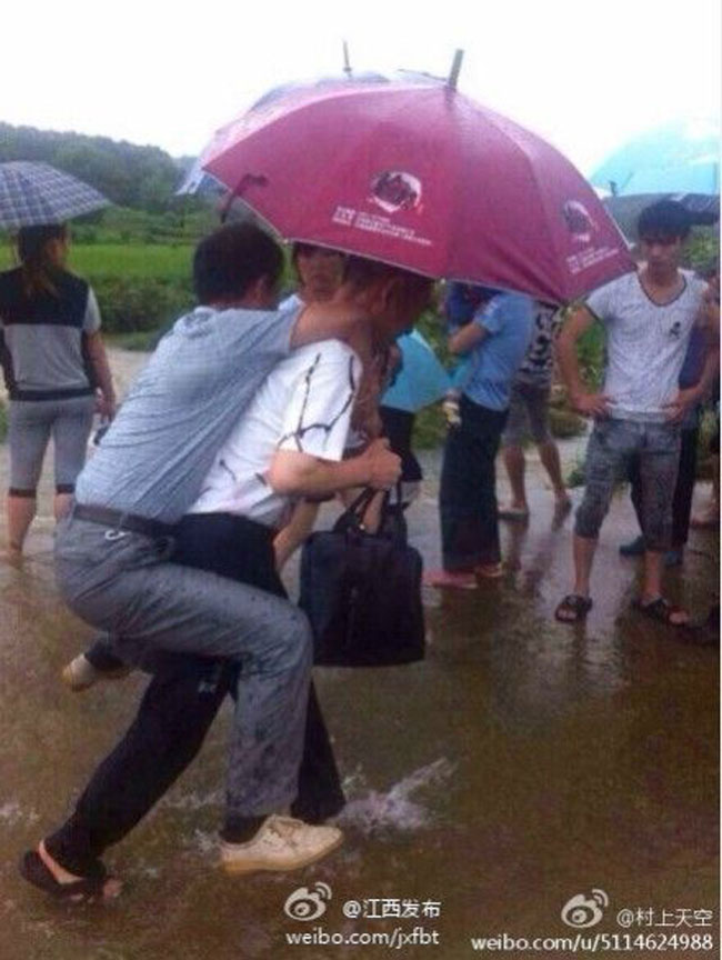 Wang Junhua, a government official in the city of Guixi, southeast China's Jiangxi province, was removed from office on June 22, 2014, after a photo of him being carried on the back of a subordinate to avoid getting wet at a flood-rescue site, where two students went missing last Friday, went viral and sparked outrage online. [Photo / Weibo]