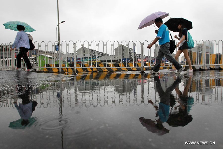 People walk under umbrellas in east China's Shanghai Municipality, June 26, 2014. Parts of Shanghai received torrential rain Thursday. [Photo/Xinhua]