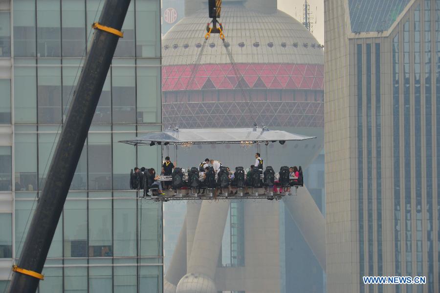 A 22-seat restaurant is lifted in the air in Lujiazui finance zone in Pudong of east China&apos;s Shanghai, June 27, 2014. A hotel in Shanghai launched a three-day service &apos;dinner in the sky&apos; on Friday. Diners were seated at a table suspended from a crane at the height of 50 meters. (Xinhua/Shen Chunchen)