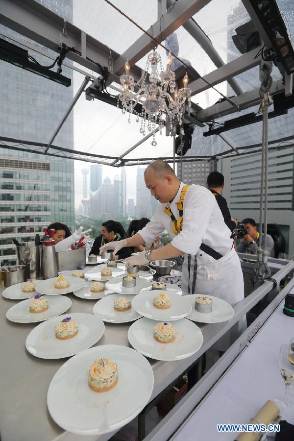 A chef prepares food for dinners at a 22-seat restaurant lifted in the air in Lujiazui finance zone in Pudong of east China&apos;s Shanghai, June 27, 2014. A hotel in Shanghai launched a three-day service &apos;dinner in the sky&apos; on Friday. Diners were seated at a table suspended from a crane at the height of 50 meters. (Xinhua/Shen Chunchen)