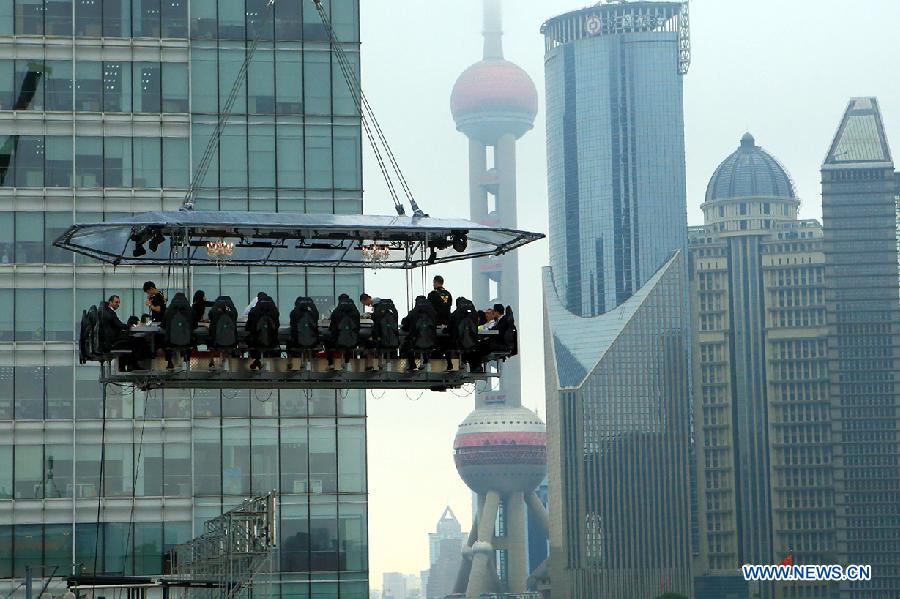 A 22-seat restaurant is lifted in the air in Lujiazui finance zone in Pudong of east China&apos;s Shanghai, June 27, 2014. A hotel in Shanghai launched a three-day service &apos;dinner in the sky&apos; on Friday. Diners were seated at a table suspended from a crane at the height of 50 meters. (Xinhua/Shen Chunchen)