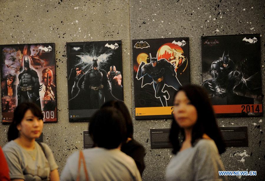 People stand in front of pictures of animation character of Batman at a shopping center as part of Batman 75th anniversary exhibition in Jakarta, Indonesia, June 27, 2014. 