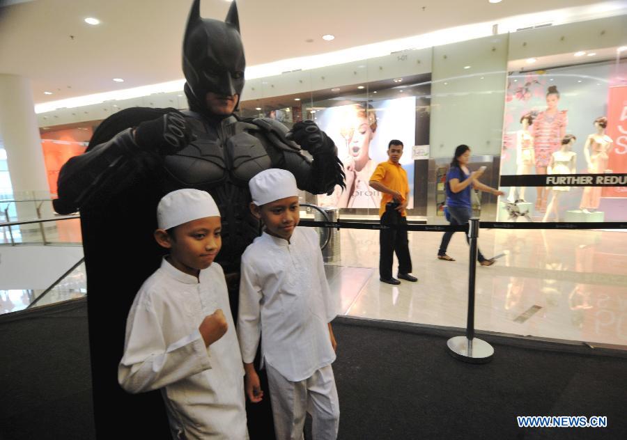 Children pose with a man wearing costumes of animation character of Batman at a shopping center as part of Batman 75th anniversary exhibition in Jakarta, Indonesia, June 27, 2014.