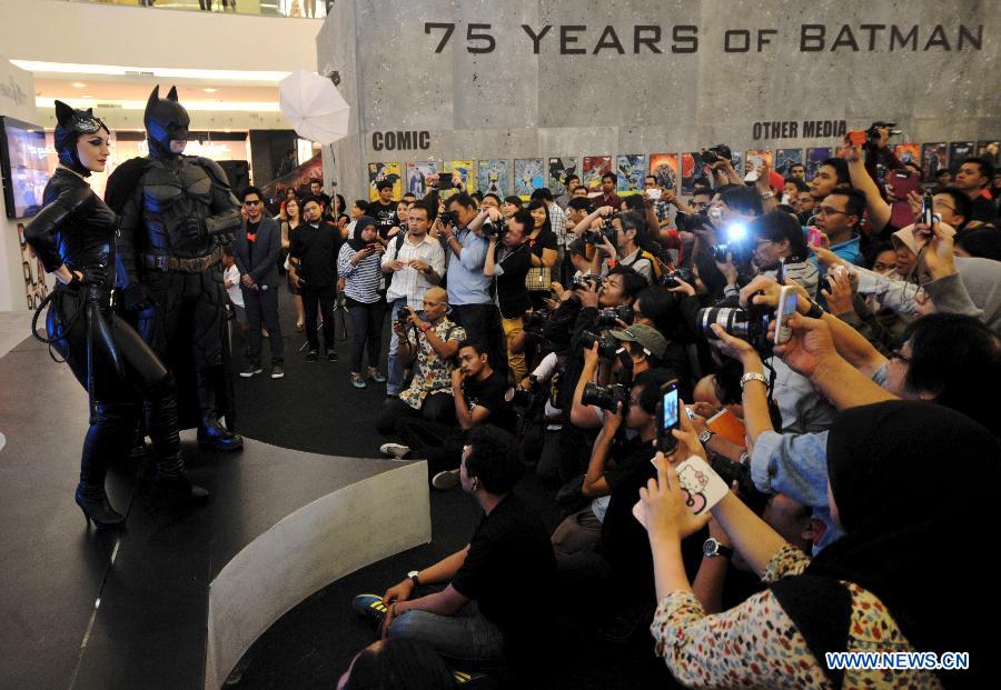 People take photos of a man wearing costumes of animation character of Batman at a shopping center as part of Batman 75th anniversary exhibition in Jakarta, Indonesia, June 27, 2014