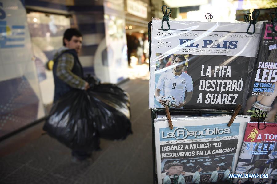 A newspaper with the image of Uruguayan player Luis Suarez is displayed for sale in Montevideo, capital of Uruguay, on June 27, 2014. Luis Suarez was banned by FIFA for four months from any football-related activity on June 26 for biting Italy&apos;s player Giorgio Chellini in a Group D match between Italy and Uruguay on June 24.