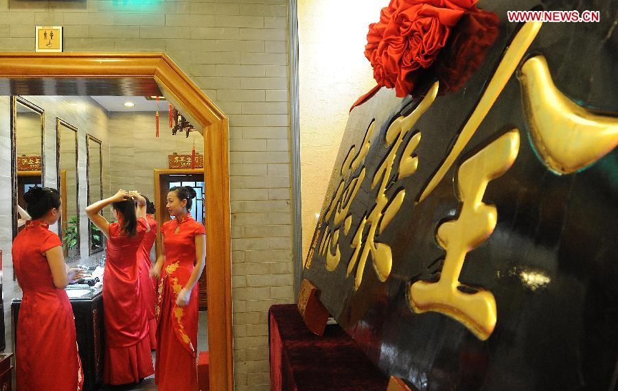 Waitresses prepare for a ceremony for the 150th anniversary of Quanjude Beijing Roast Duck Restaurant at its Qianmen Branch in Beijing, capital of China, July 2, 2014. 