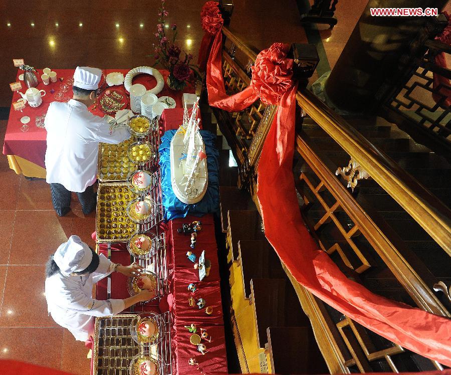 Staff members are busy arranging showcase for a ceremony for the 150th anniversary of Quanjude Beijing Roast Duck Restaurant at its Qianmen Branch in Beijing, capital of China, July 2, 2014. 