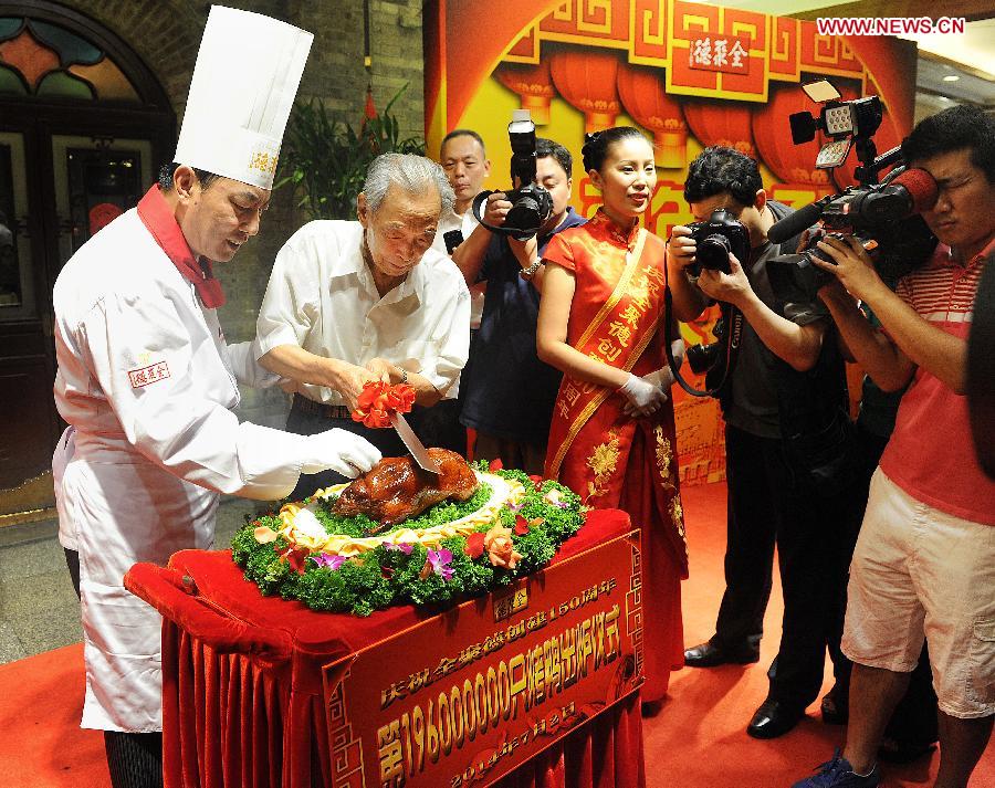Yang Dengyan (2nd L), the first president of Quanjude Group, slices Quanjude&apos;s 196 millionth roast duck during a ceremony to celebrate the 150th anniversary of Quanjude Beijing Roast Duck Restaurant at its Qianmen Branch in Beijing, capital of China, July 2, 2014. 