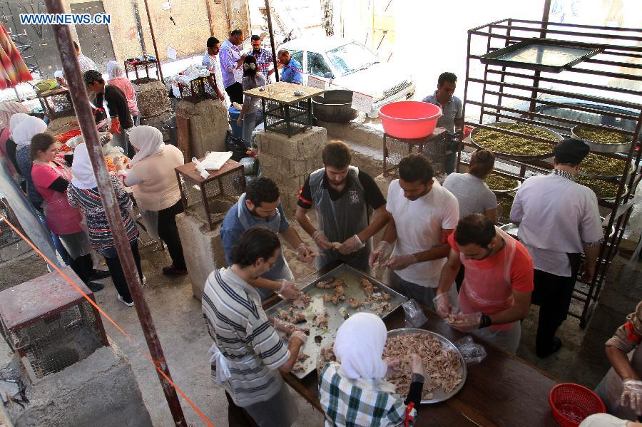 A group of Syrian volunteers prepare meals to be distributed later to the needy, at a makeshift charity kitchen in Damascus, capital of Syria, July 4, 2014. The meals will be distributed during the Muslims&apos; holy month of Ramadan, during which Muslims abstain from food, drink and sex from sunrise to sunset. Some non-government groups assist those displaced by offering the meals.