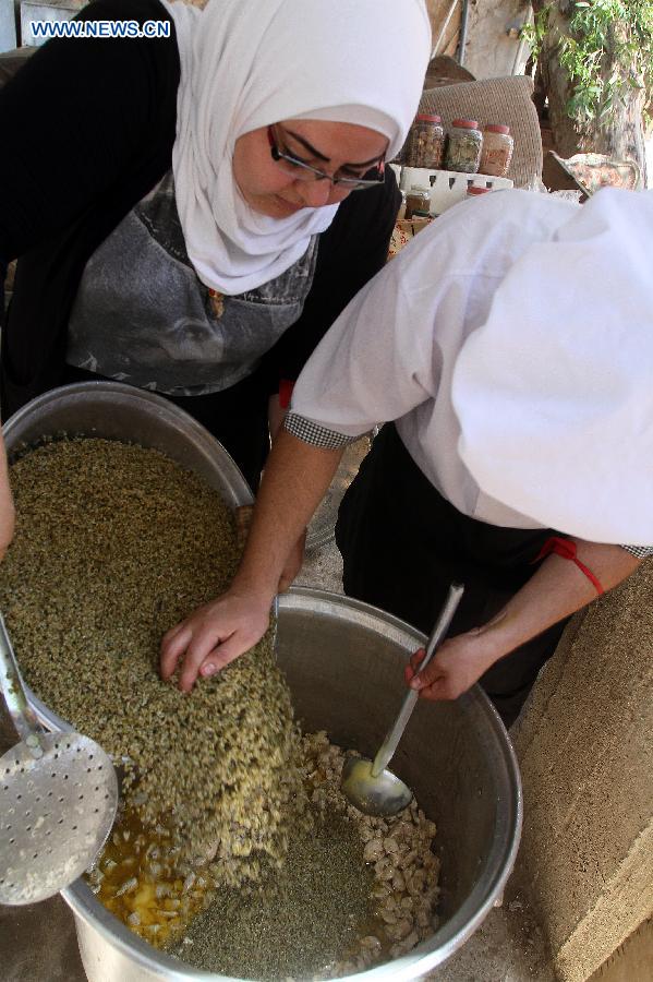 Syrian volunteers prepare meals to be distributed later to the needy, at a makeshift charity kitchen in Damascus, capital of Syria, July 4, 2014. The meals will be distributed during the Muslims&apos; holy month of Ramadan, during which Muslims abstain from food, drink and sex from sunrise to sunset. Some non-government groups assist those displaced by offering the meals.